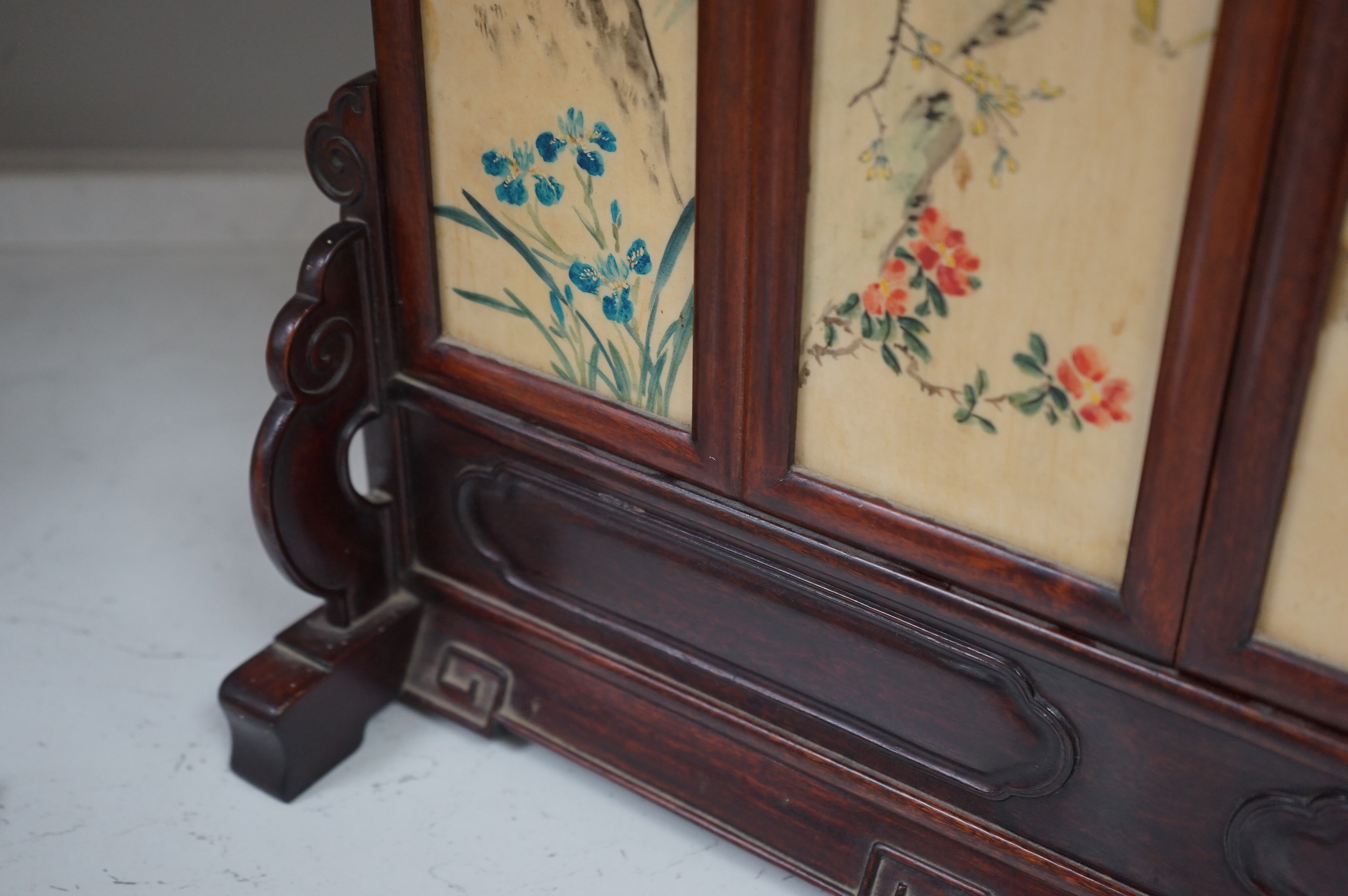 A Chinese four painted porcelain panel and carved hardwood table screen, 54cm wide x 42.5high. Condition - fine staining to one panel and top carved panel of screen missing